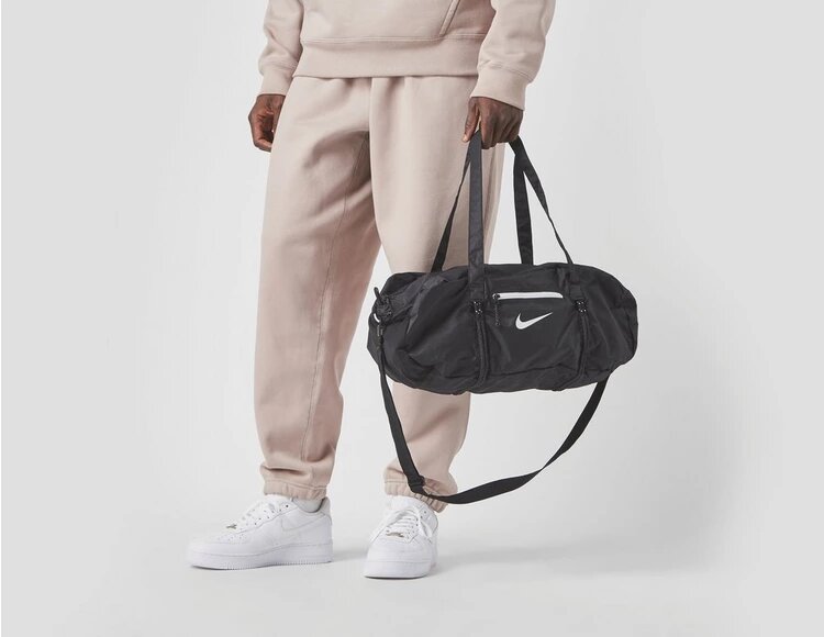 Un uomo che porta a mano uno zaino da sport nero tash del marchio Nike