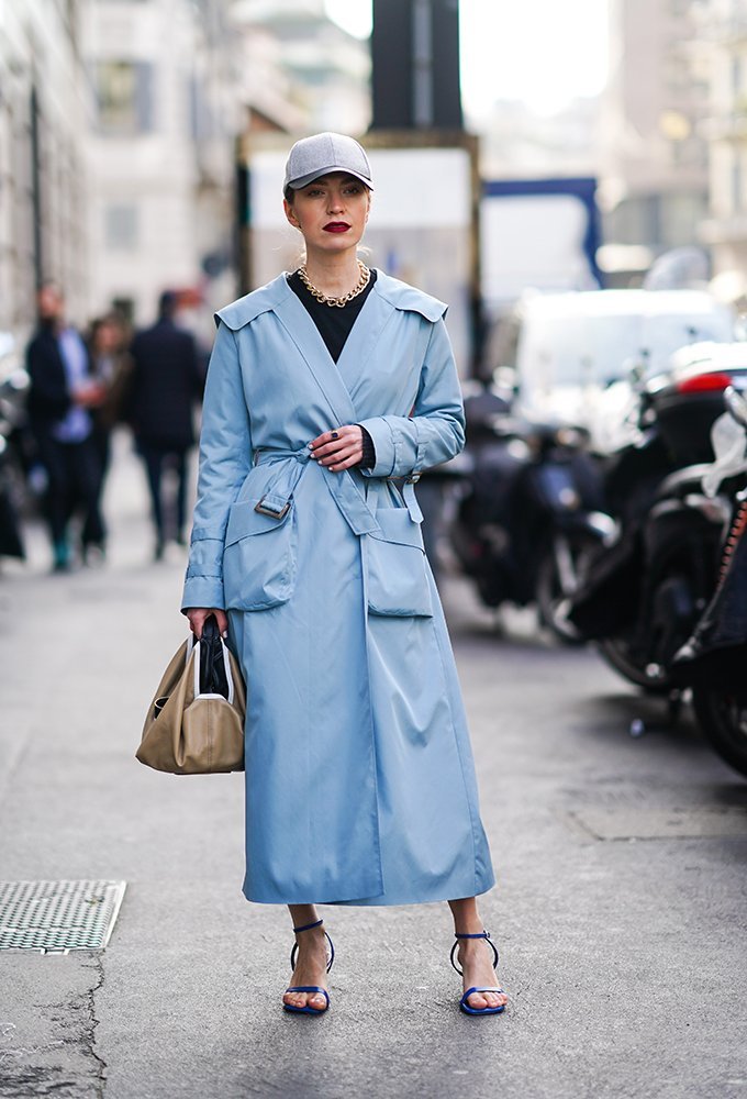 Donna con una berretto fitted e un lungo trench blu