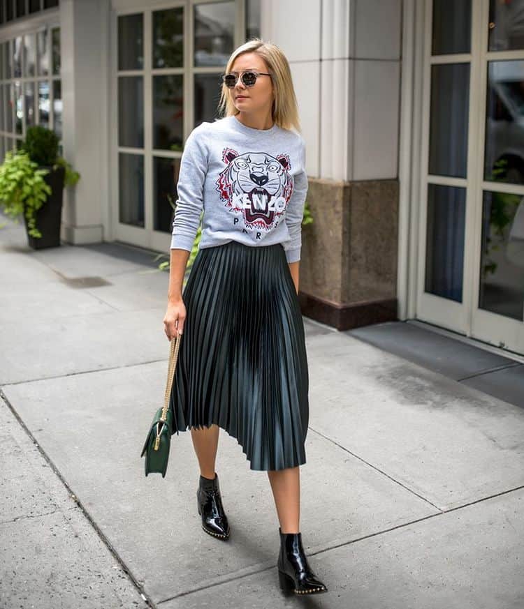 Donna che indossa una felpa grigia con una gonna plissettata e stivaletti