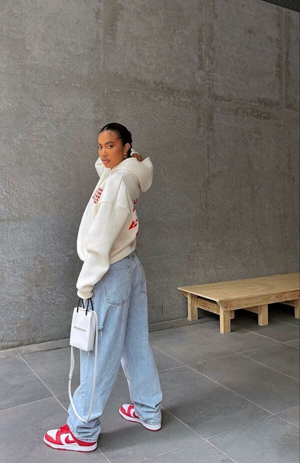 Donna che indossa una felpa bianca e un paio di jeans boyfriend con sneakers