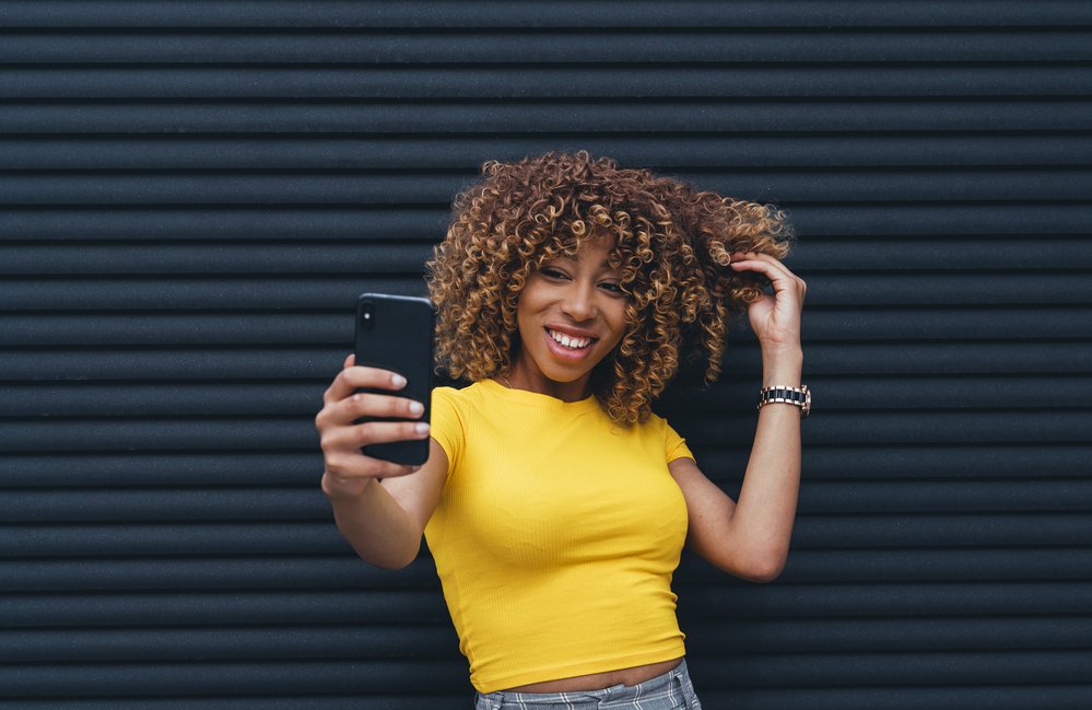 Donna che indossa una maglia gialla scattando un selfie