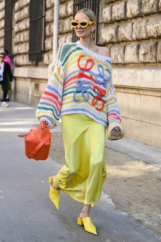 Donna che indossa una valigia lavorata a maglia sopra un vestito per strada.